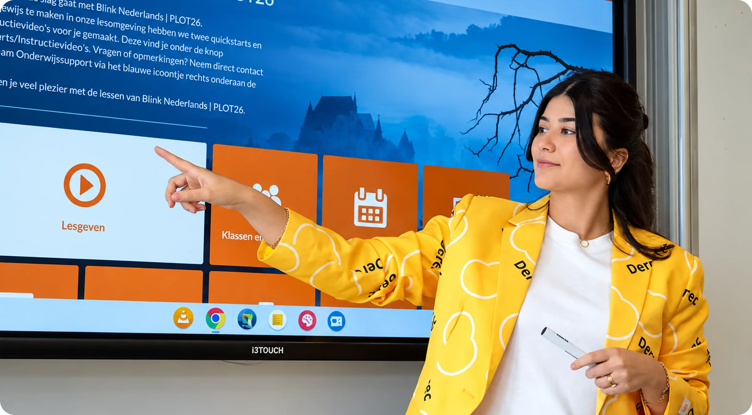 Een medewerker van DEREC wijst iets aan op een digibord in een klaslokaal