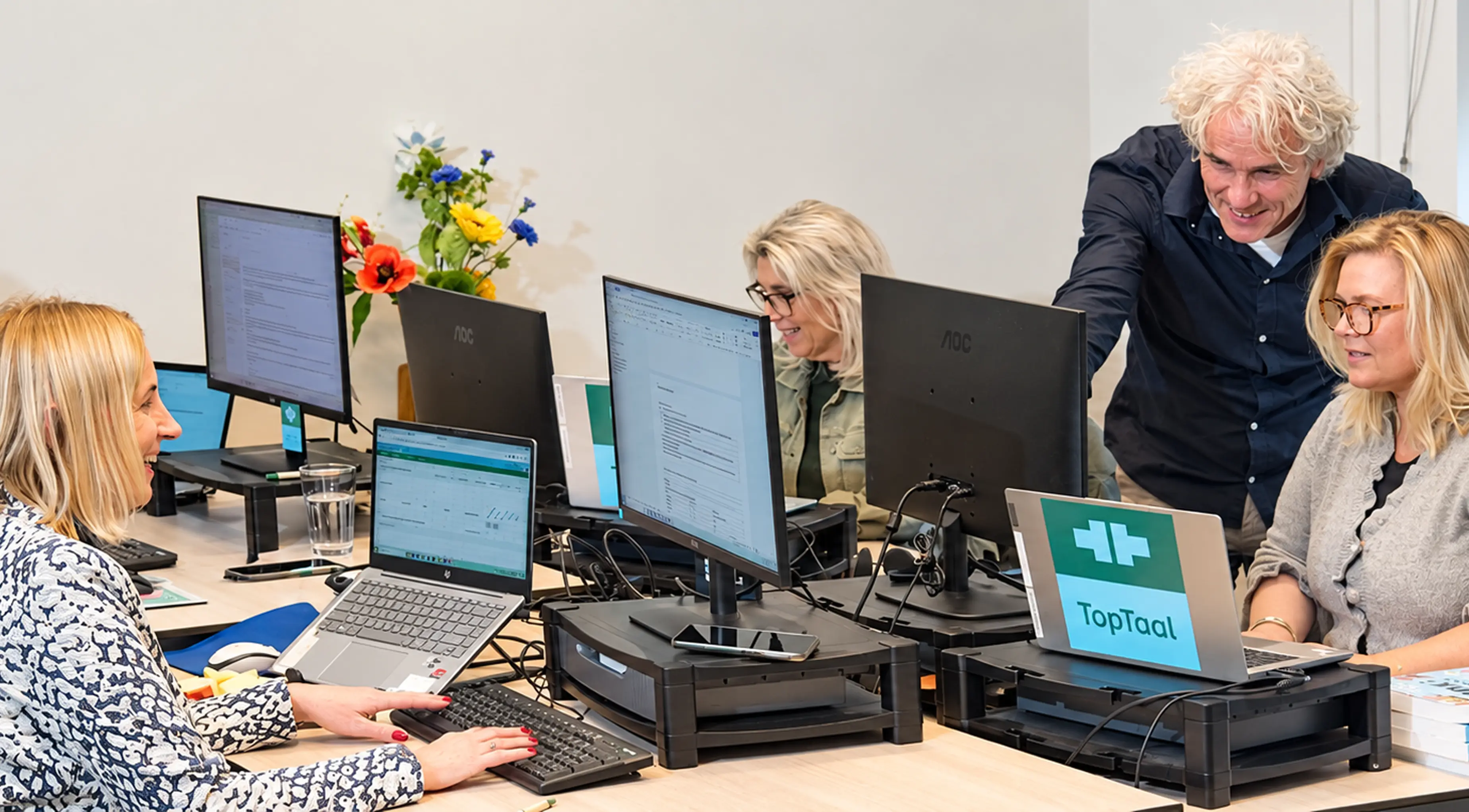 Medewerkers van TopTaal werken samen achter hun schermen